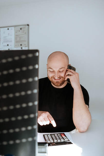 Freundliches Telefongespräch in der Zentrale Mitarbeiter sitzt in der Zentrale am Schreibtisch und führt ein Telefonat mit einem Lächeln.